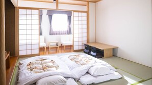 Una habitació japonesa tradicional amb fons de tatami, un llit futón, un taulell de fusta baix i un panell corregut shoji.