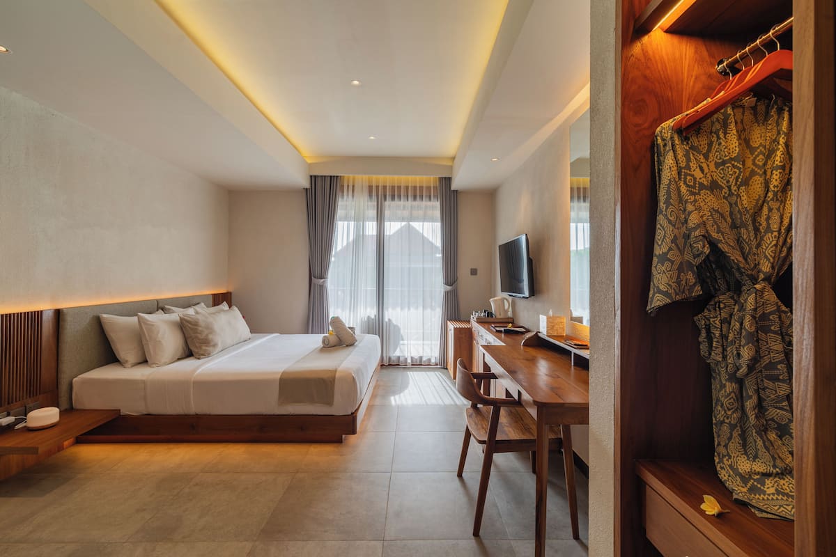 A hotel room with a bed, desk, TV, and a wardrobe.