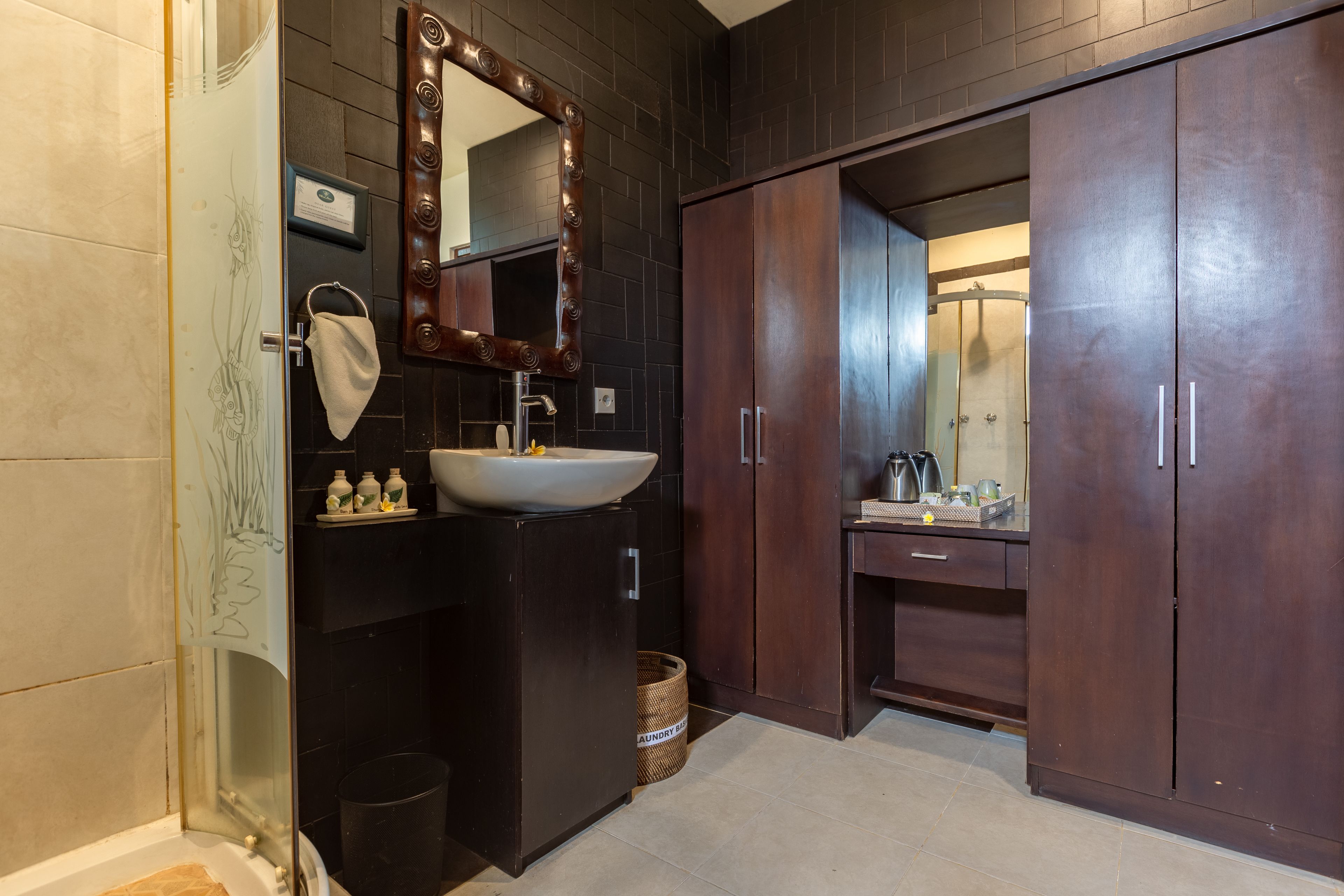 A bathroom with a dark wood vanity, a white sink, and a mirror with a decorative frame.