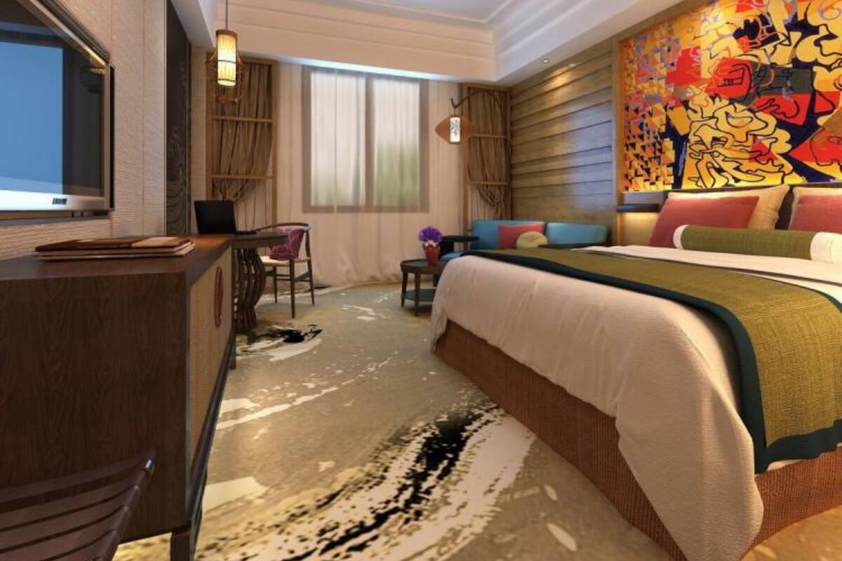 Ein modernes Hotelzimmer mit einem großen Bett, einem Schreibtisch und einem Fernseher.