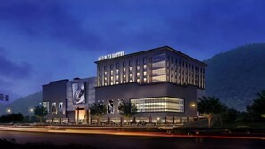 A modern hotel building with a prominent sign, large windows, and a flat roof.