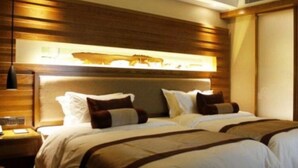 A hotel room with a large bed, two bedside tables, a nightstand, and a wall-mounted light fixture.