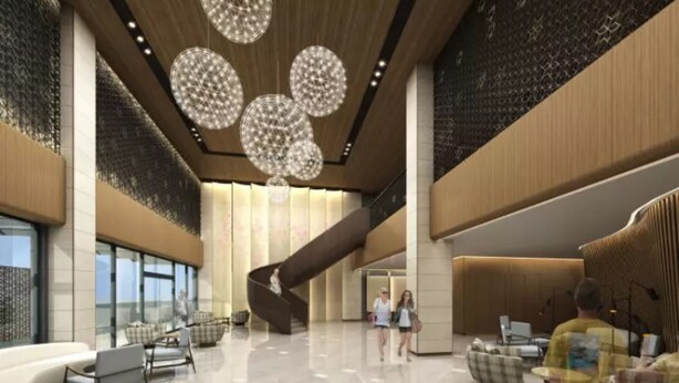 A spacious lobby with a central staircase, modern lighting, and seating areas.
