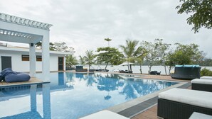 A swimming pool with lounge chairs and a covered seating area. - Flow by The Amber Collection - Luxury River Cruises in Sri Lanka (Piliyandala)
