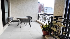 A balcony with a table and chairs, a potted plant, and a decorative railing. - Happiness 1799 (Hualien City)