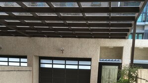An open covered area with tiled flooring, a metal roof structure, and a large garage door. - Happiness 1799 (Hualien City)
