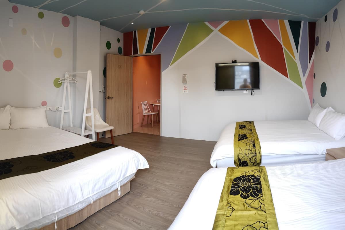 Una habitación de hotel con dos camas, un televisor montado en la pared y un diseño de techo colorido.