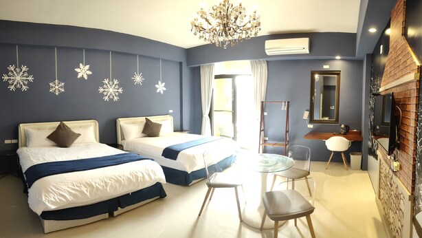 A hotel room with two beds, a chandelier, an air conditioning unit, a mirror, and a small table with chairs. - Happiness 1799 (Hualien City)