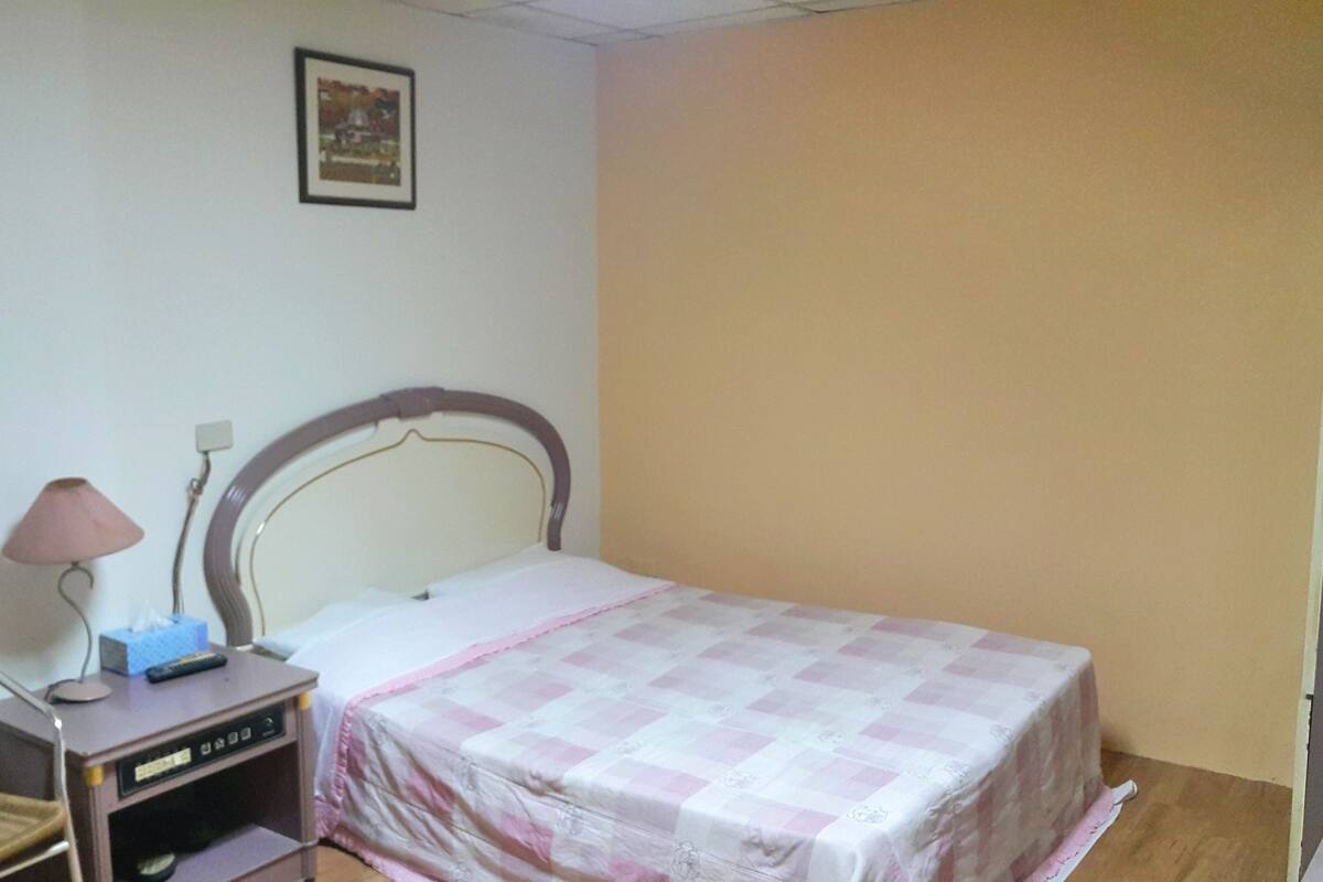A bedroom with a single bed, a bedside table with a lamp, and a chair.