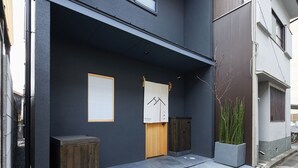A modern building with a dark facade, a wooden door, and a small wooden cabinet.