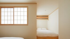 A bedroom with a large window, a bunk bed, and a wooden floor.