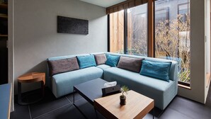 A modern living room with a light blue sofa, a wooden coffee table, and a small side table.