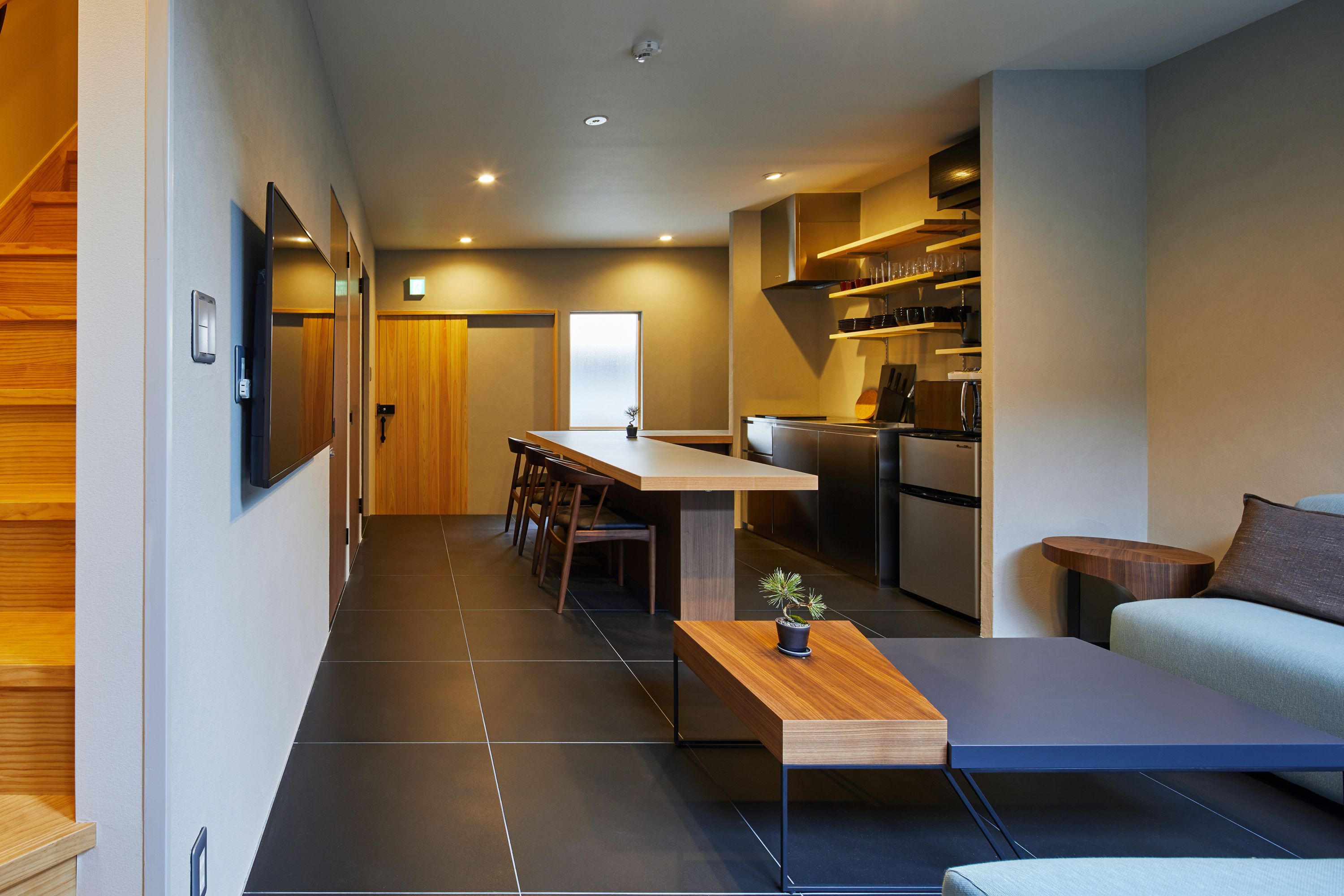 Une cuisine moderne avec un coin repas, un canapé et une petite table agrémentée d’une plante.