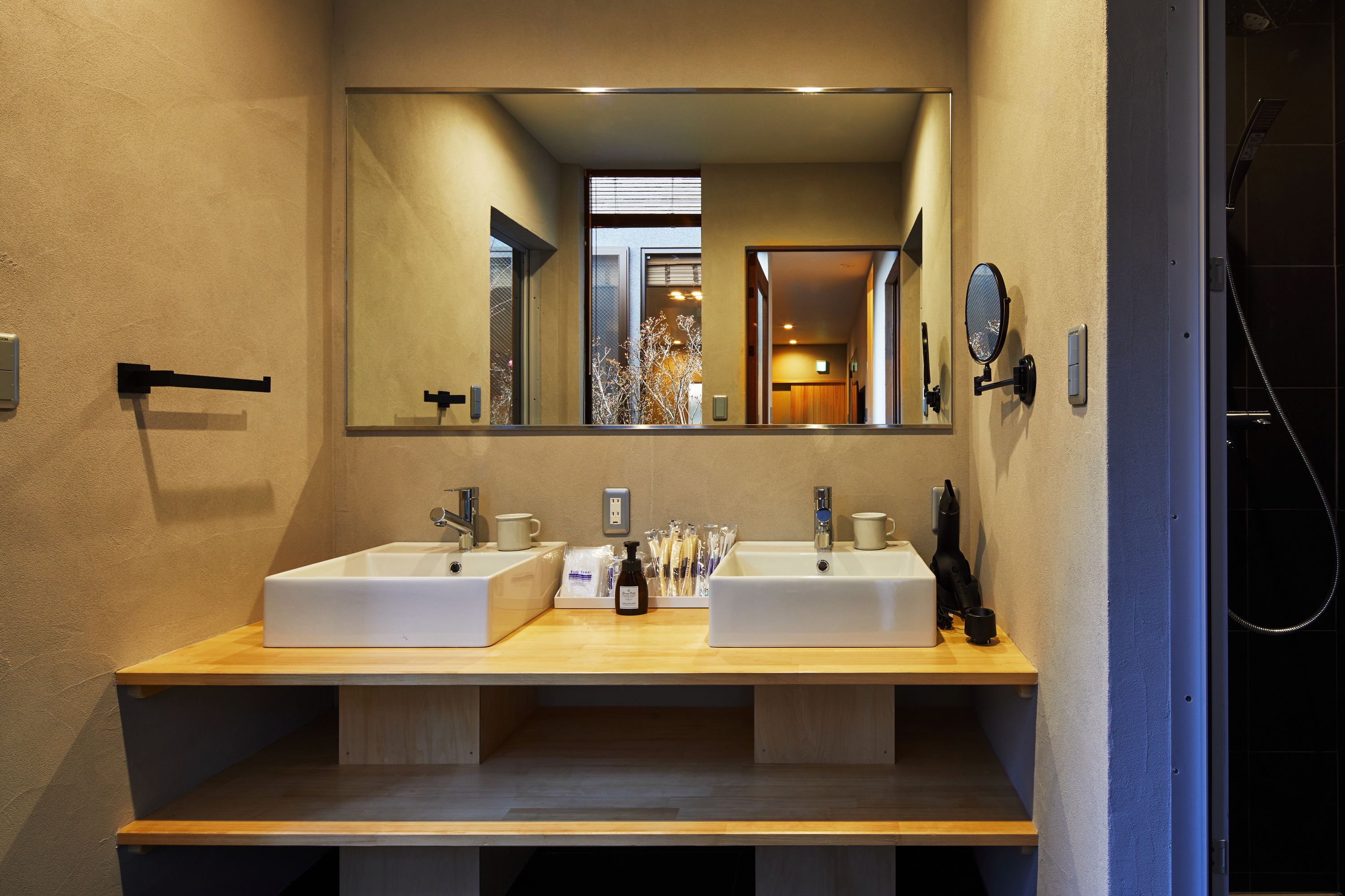 Un baño moderno con dos lavamanos, un espejo grande y una zona de ducha.