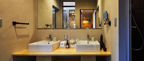 Un baño moderno con dos lavamanos, un espejo grande y una zona de ducha.