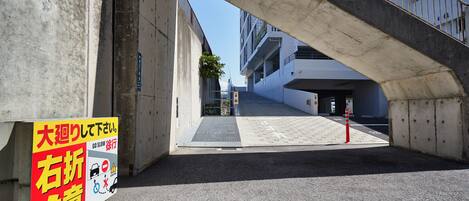 A concrete bridge with a sign in Japanese, a ramp, and a building in the background.