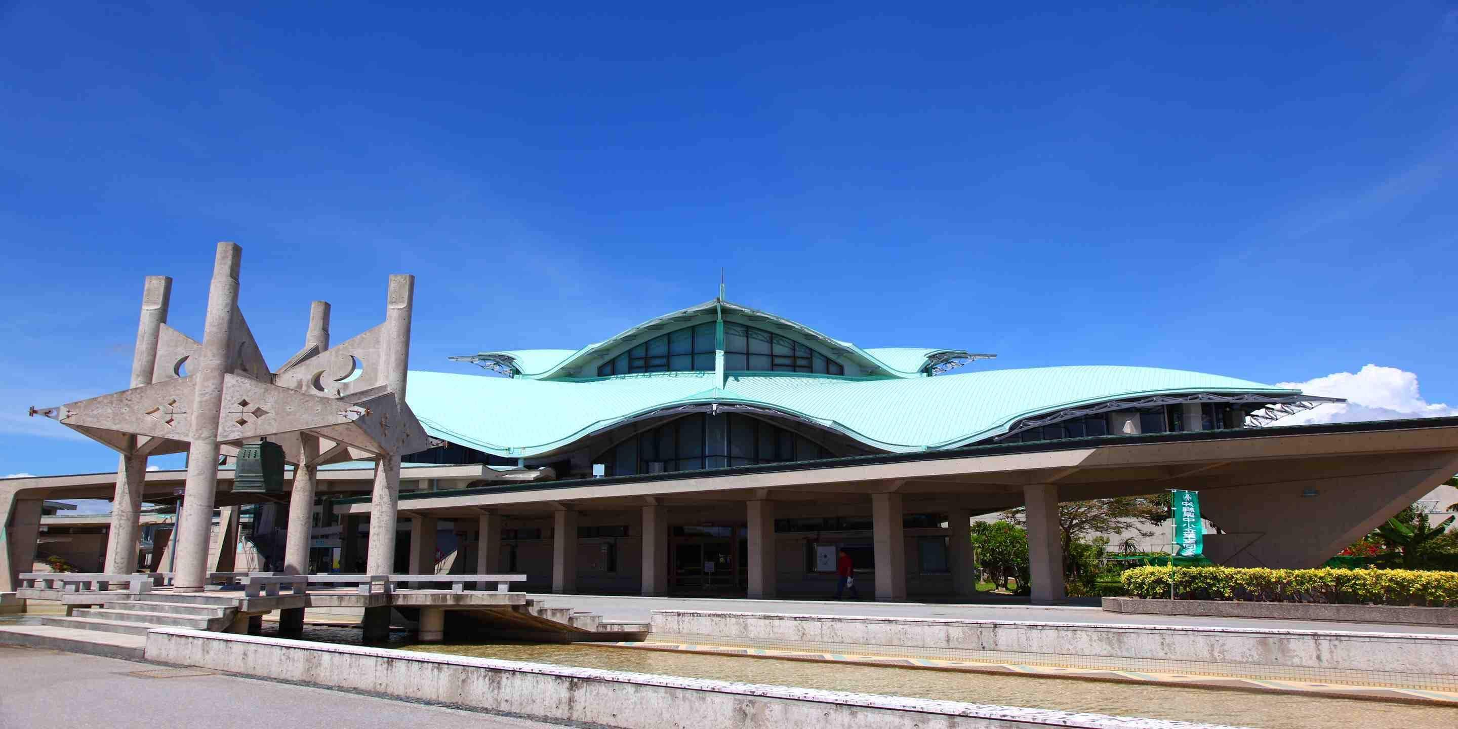 A modern building with a unique architectural design, featuring a curved roof and multiple columns.