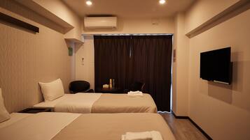 Une chambre d’hôtel avec deux lits, une télévision, la climatisation et un bureau avec une chaise.