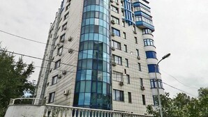 A multi-story hotel with a curved glass facade, multiple balconies, and a classic architectural design. - Apart Hotel Keremet (Almaty)