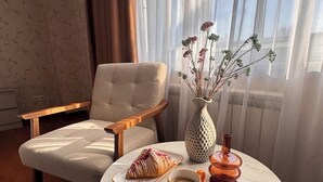 A cozy room with a round table set for breakfast, including a pastry, a cup of coffee, and a vase with dried flowers. - Apart Hotel Keremet (Almaty)