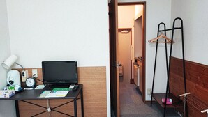 Une chambre d’hôtel équipée d’un bureau, d’un ordinateur portable, d’une bouilloire, d’une horloge et d’un porte-manteau.