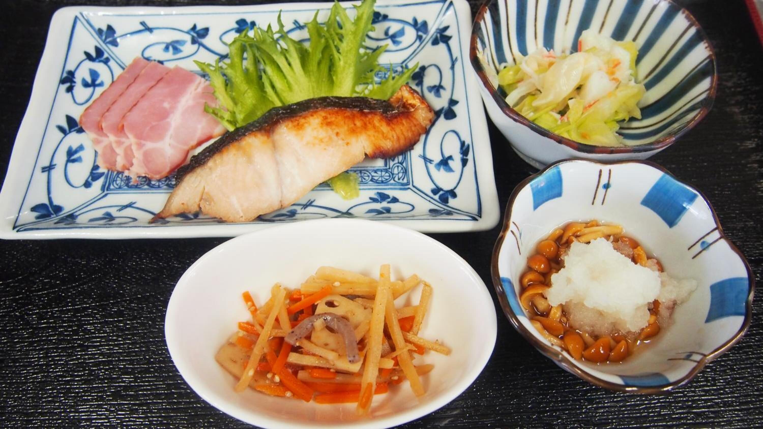 A plate with fish, vegetables, and a bowl of beans.