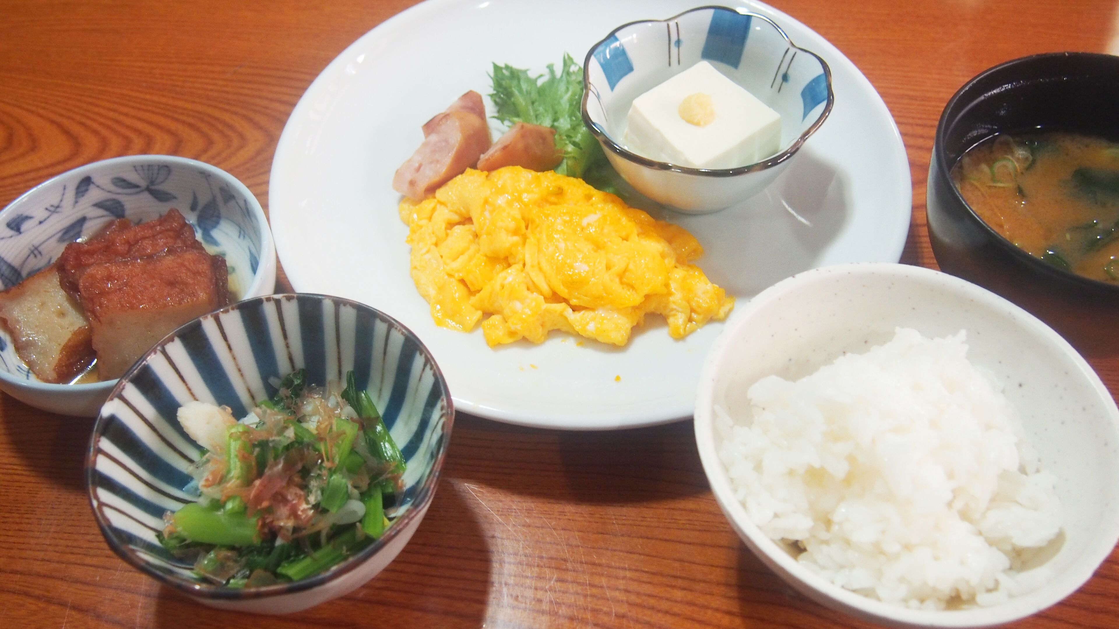 A table with various dishes including rice, scrambled eggs, and a bowl of soup.
