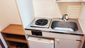 Une petite cuisine équipée d’une cuisinière, d’un évier et d’un petit réfrigérateur.