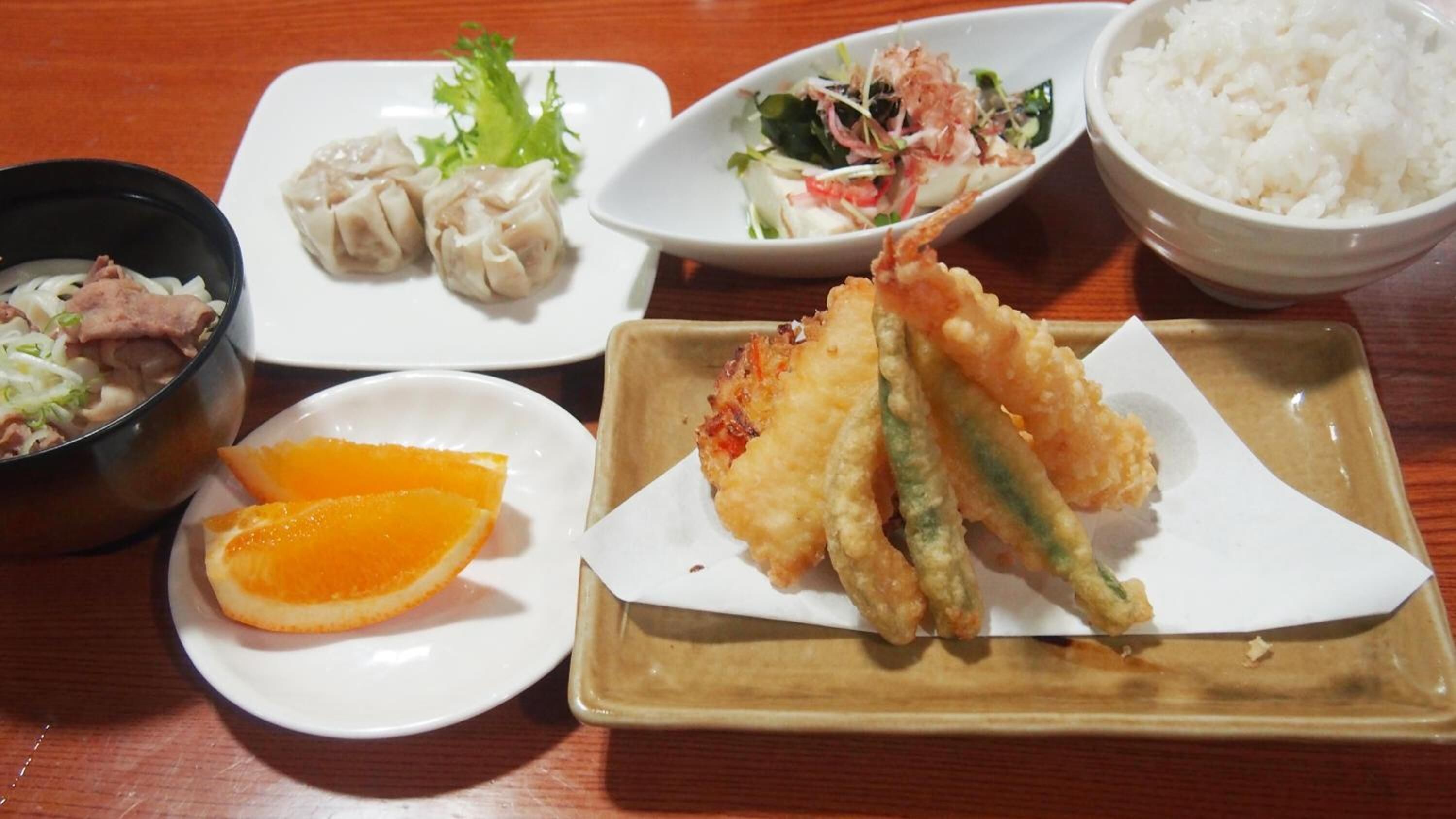 A table with various dishes including sushi, tempura, and rice.