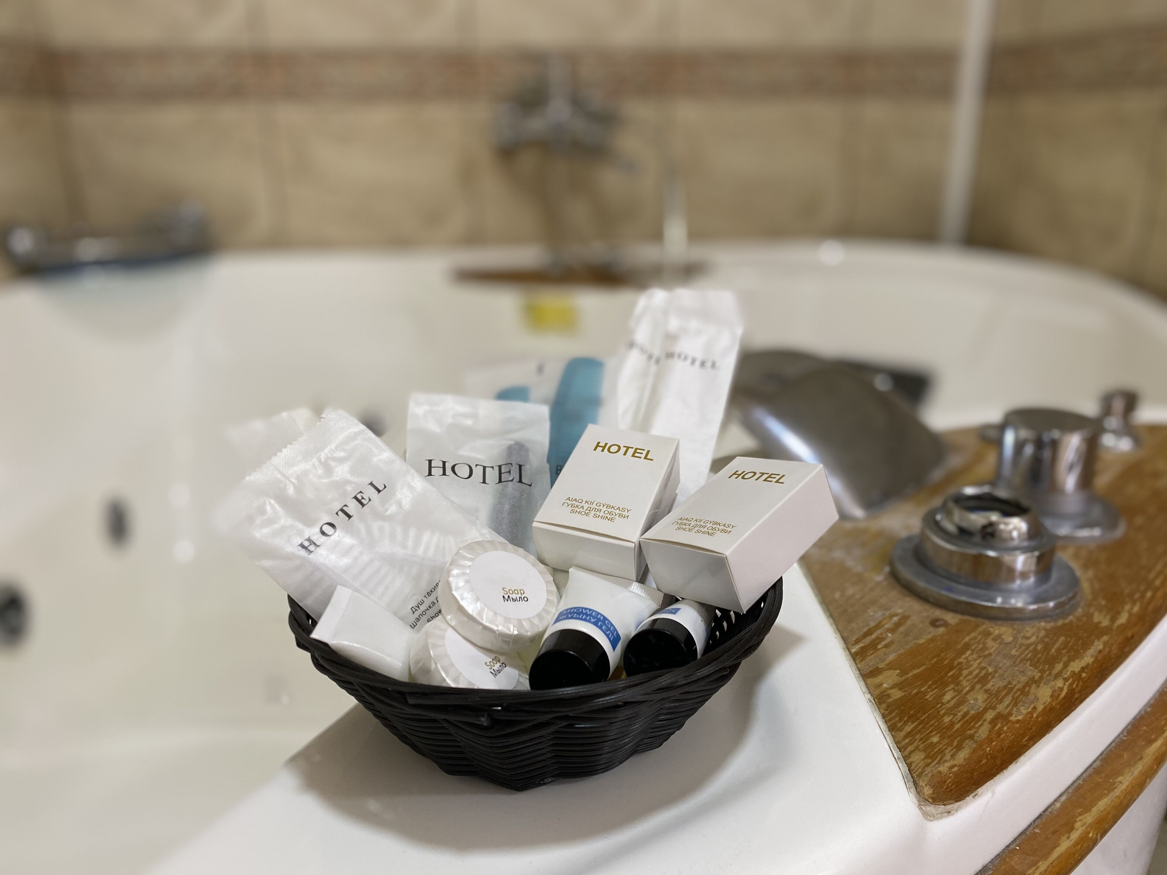 A basket of toiletries on a bathroom counter next to a bathtub.