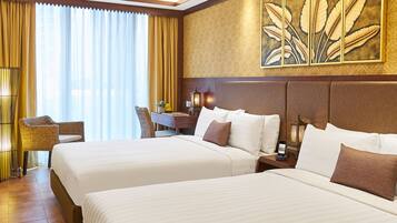A hotel room with two beds, a desk, a chair, and a large window with curtains.