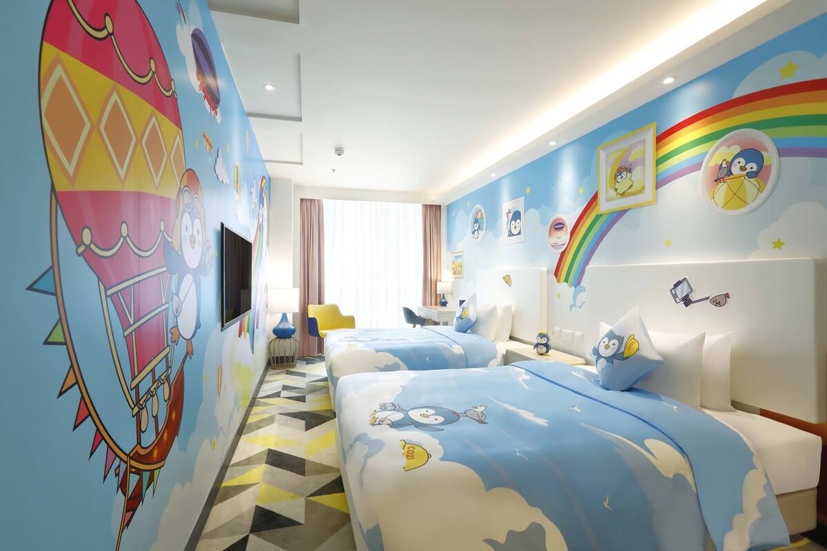 A hotel room with two beds, a large window, and a colorful mural on the wall.