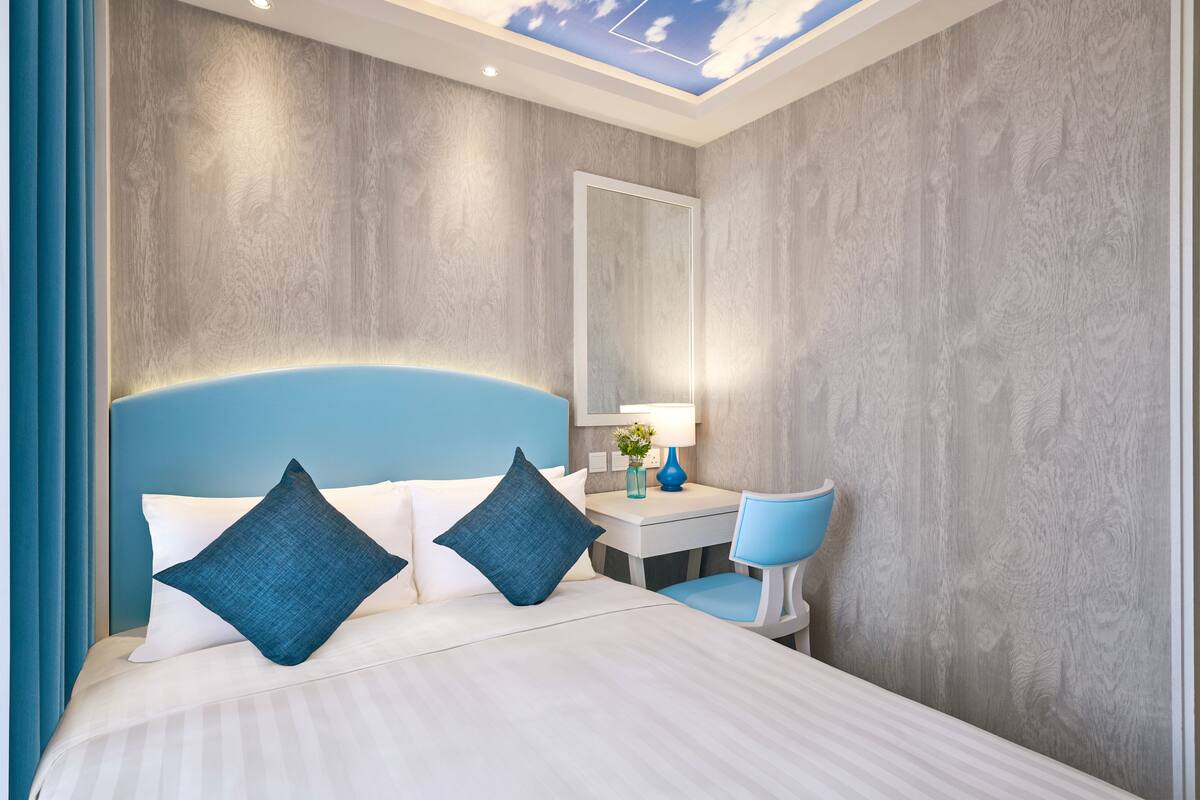 A modern hotel room with a large bed, a desk, and a chair.