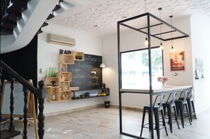 Zona de bar moderna con un menú en pizarra, cajas de madera y una escalera.