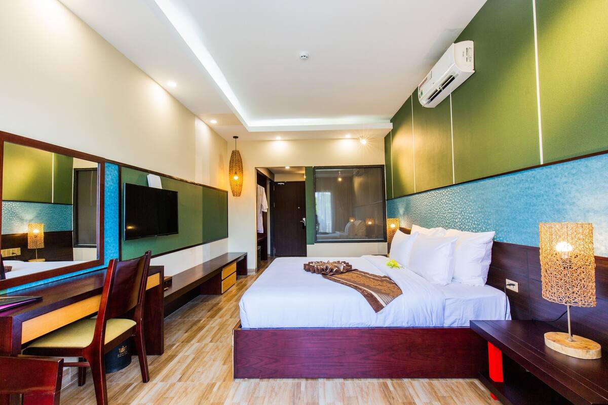 Une chambre d’hôtel moderne dotée d’un grand lit, d’un bureau avec une chaise, d’une télévision et d’un grand miroir.