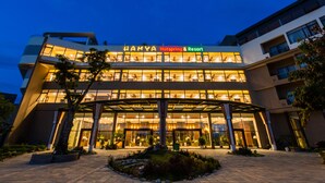 Um hotel moderno com fachada de vidro, entrada destacada e exterior bem iluminado.