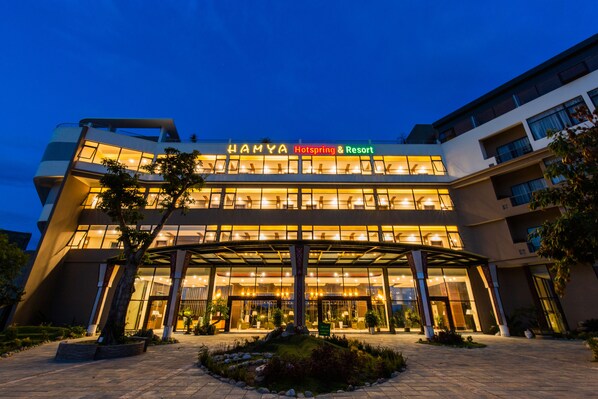 A modern hotel with a glass facade, a prominent entrance, and a well-lit exterior.