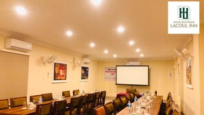 A conference room with long tables, chairs, and a projector screen. - Hotel Boutique Lacoul Inn (Siddharthanagar)