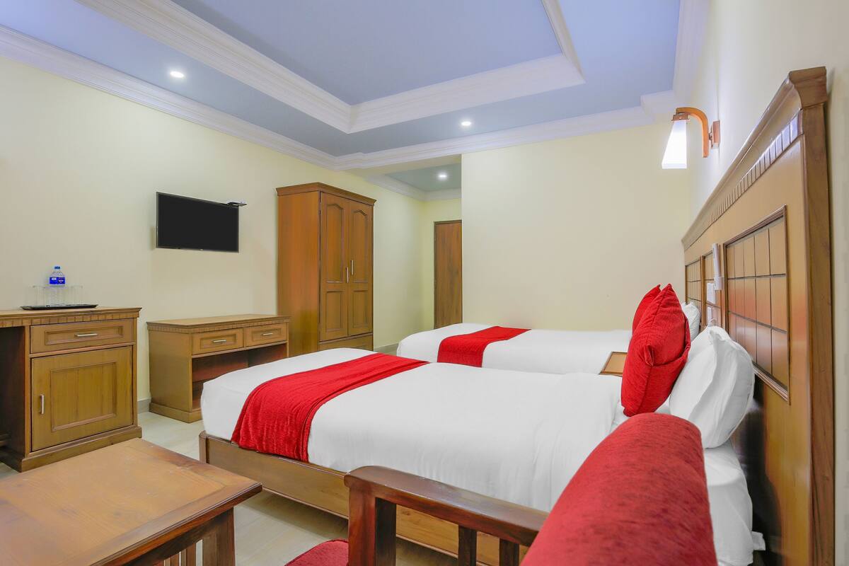 A hotel room with two beds, a desk, and a wardrobe.