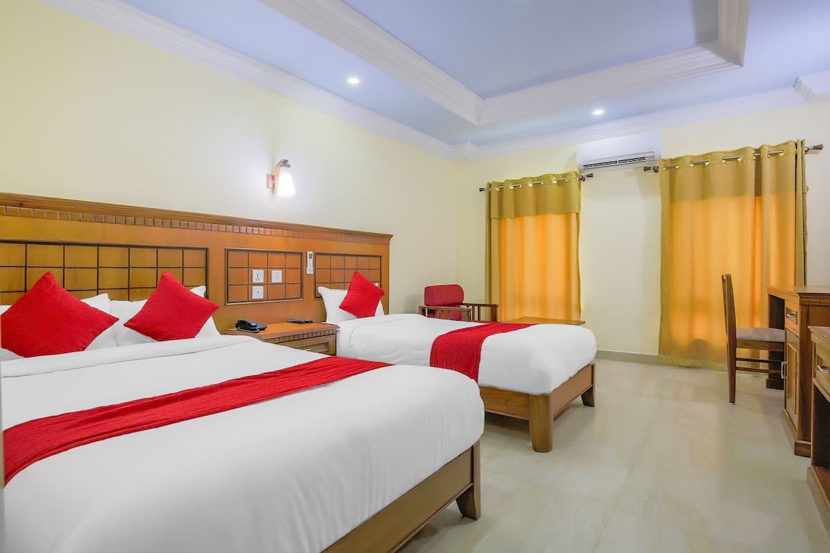 A hotel room with two beds, a desk, a chair, and an air conditioning unit.