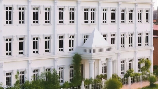 A multi-story building with a symmetrical facade, featuring evenly spaced windows and a central tower with a pointed roof. - Hotel Boutique Lacoul Inn (Siddharthanagar)