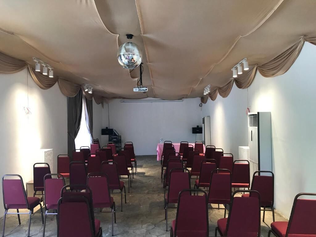 A conference room with rows of red chairs, a disco ball, and a projector screen.