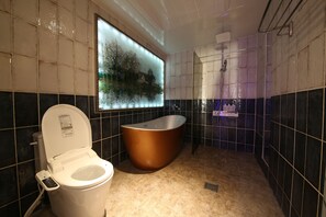 A bathroom with a bathtub, toilet, and a large window with a view of trees. - Noble Muintel (Suncheon)
