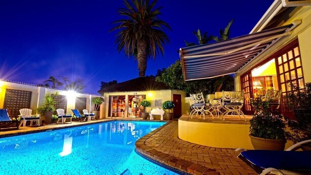 Ein Schwimmbecken mit Liegestühlen und einer überdachten Terrasse.