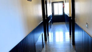 A long, narrow hallway with a marble floor and dark wooden paneling on the walls. - Hotel Kishna Palace (Dehradun)