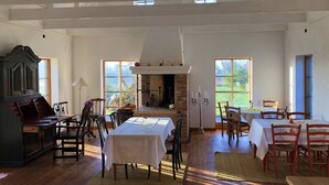 A dining area with a fireplace, wooden furniture, and large windows.