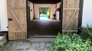 A wooden barn entrance with a brick floor leading to a pool area.