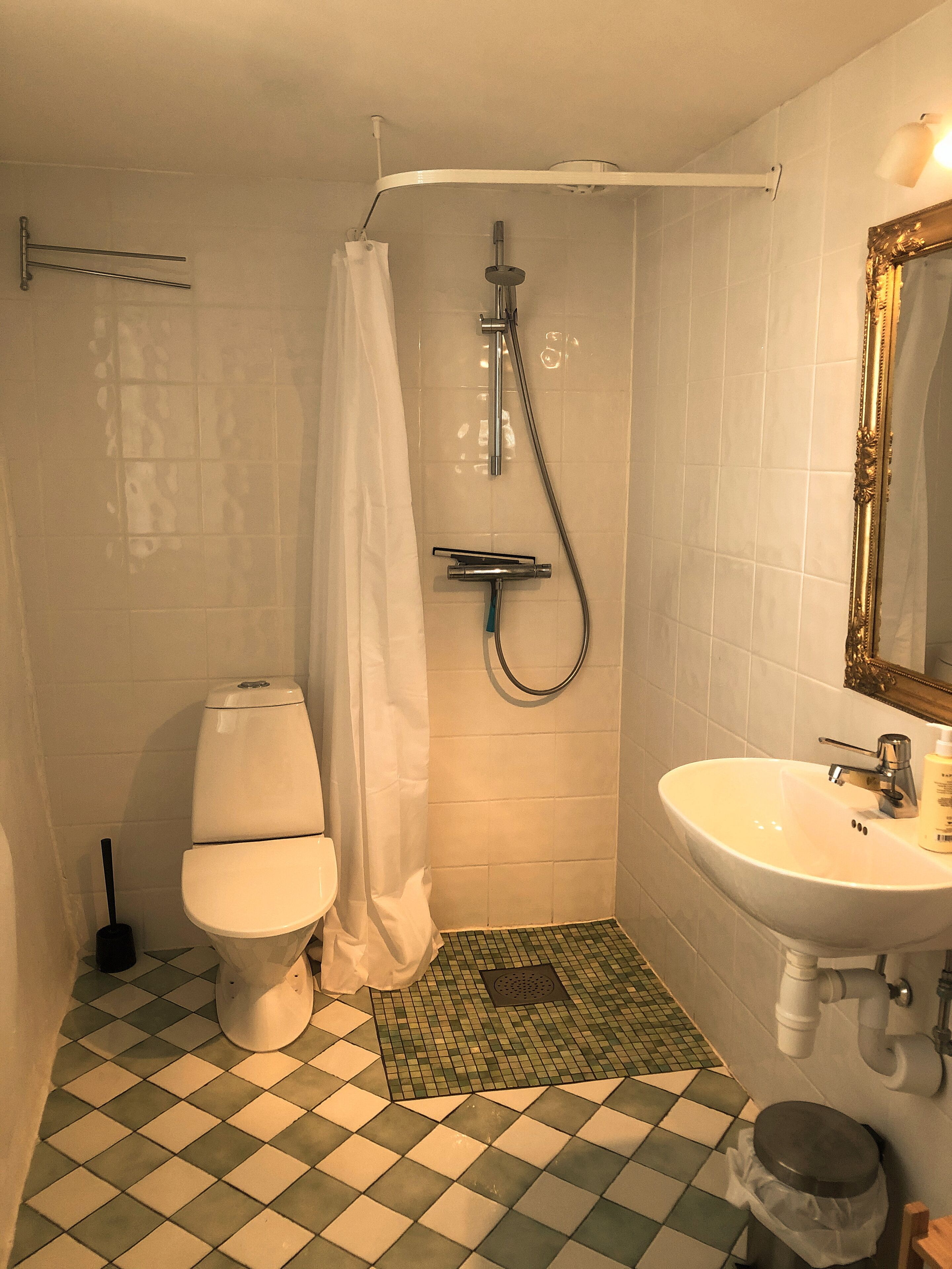 A bathroom with a toilet, shower, and sink.