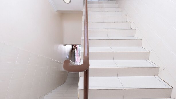 A staircase with white steps and walls, a handrail, and a sign on the wall. - Hotel O Ayuni Hotel (Bandar Baru Bangi)