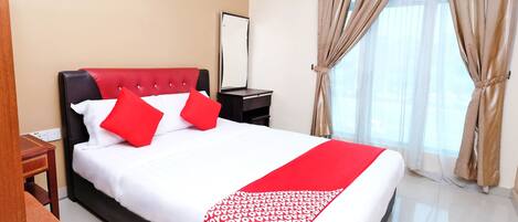 A hotel room with a bed, a nightstand, a mirror, and a window with curtains.